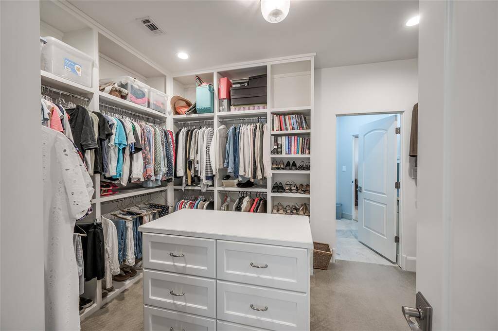 Large walk-in closet with plenty of hanging space and packing island with storage