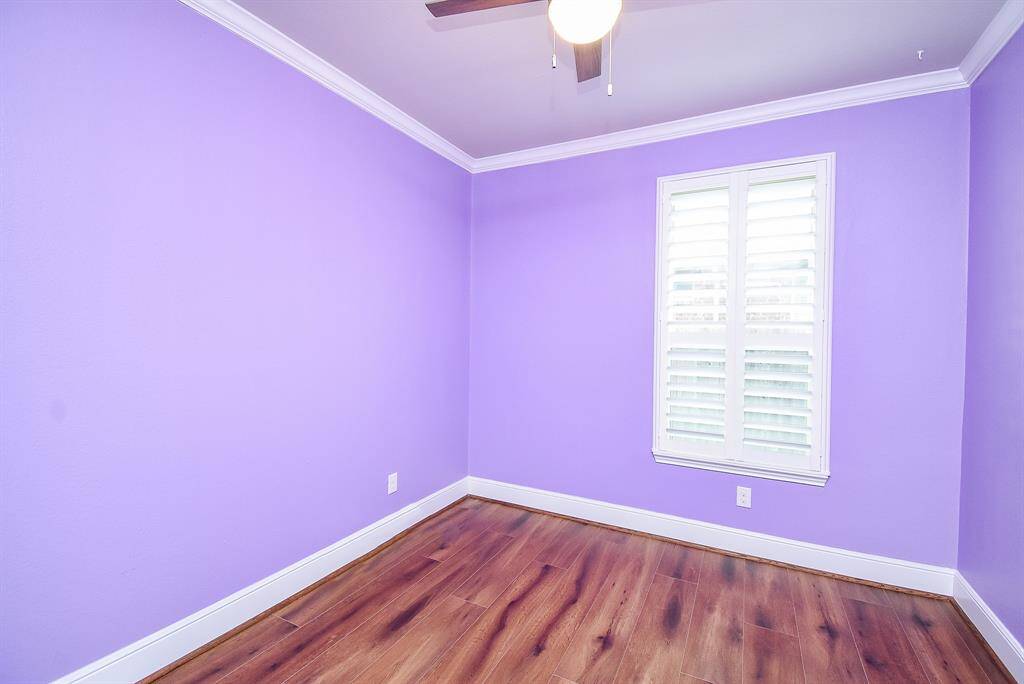 Versatile front study/flex room featuring elegant LVP flooring, plantation shutters, and custom trim and crown molding.