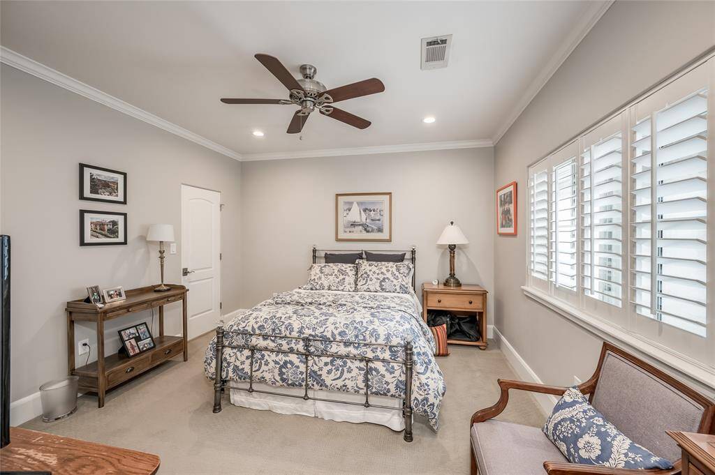 Secondary bedroom #1 features windows that invite in lots of natural light overlooking the side yard and plantation shutters, en-suite bathroom, walk-in closet, recessed lighting, and crown moulding.