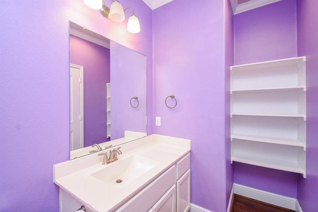 Charming guest bathroom featuring an elegant archway and built-in storage plus  custom trim and crown molding.