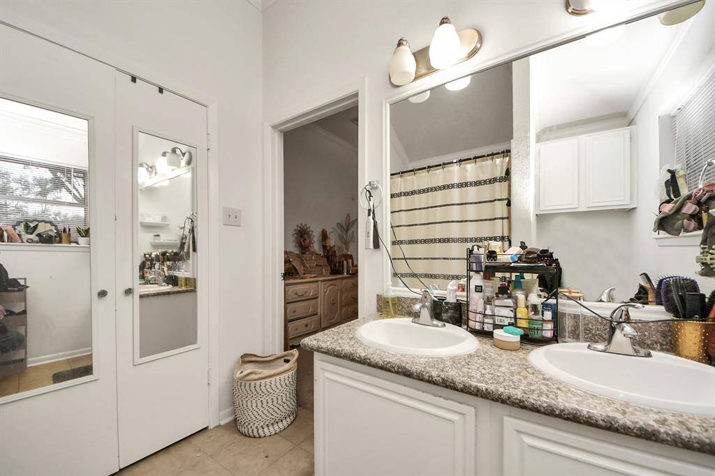 The primary bathroom has white cabinets and a large mirror.
