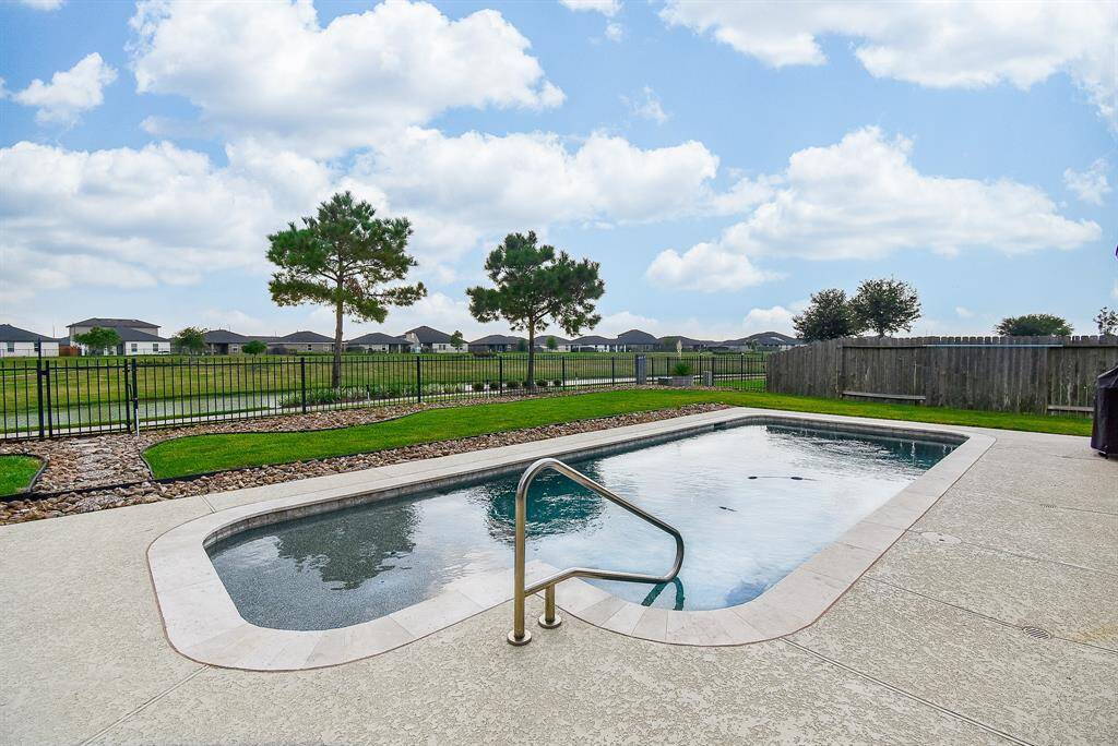 Private pool overlooks the lake featuring a splash pad with bubblers, therapeutic jets on the bench, pool light with multiple color options and dawn to dusk flood lights around the pool.