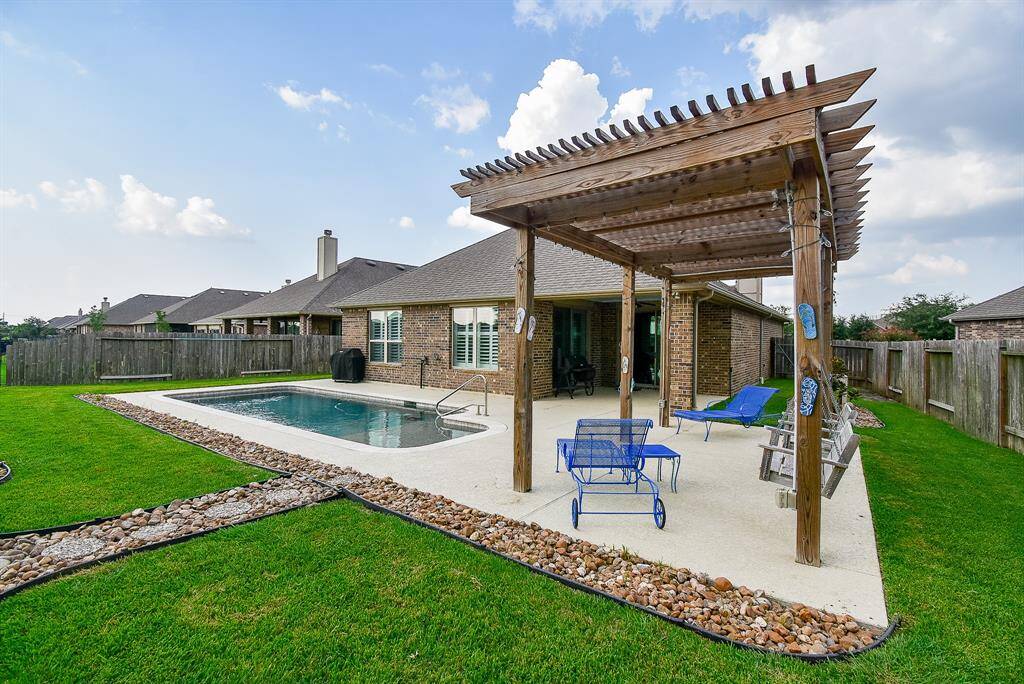 Low maintenance backyard with refreshing in-ground pool, pergola and a covered patio area, ideal for outdoor relaxation and entertainment.