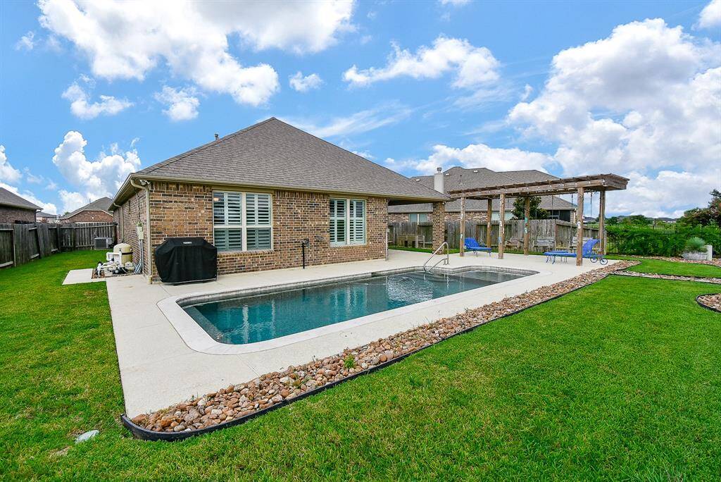 Low maintenance backyard with refreshing in-ground pool, pergola and a covered patio area, ideal for outdoor relaxation and entertainment.