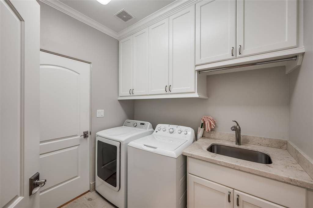 Laundry room is conveniently located on the second floor and has tile flooring, sink with cabinetry above and below.