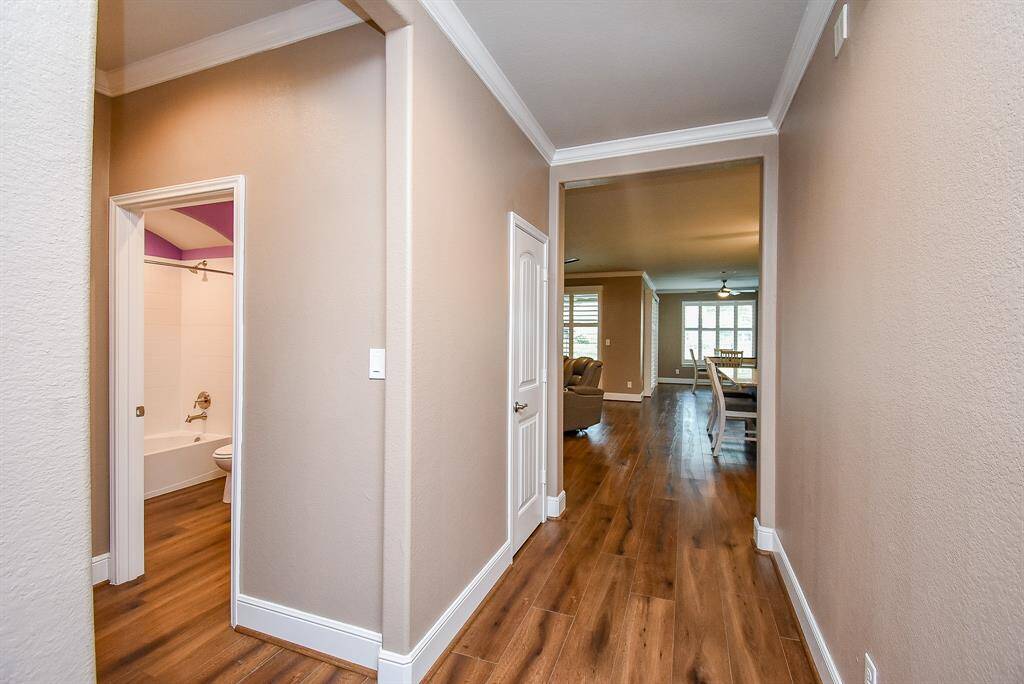 Warm-toned LVP flooring leads into a spacious, well-lit living area. This home features modern white trim and neutral wall colors, offering a clean and versatile canvas for personalization.
