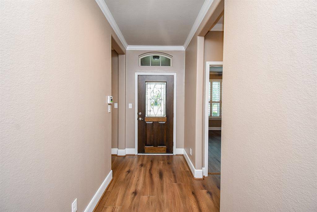 Welcoming entryway with warm-toned LVP flooring and an elegant front door featuring a decorative glass insert.