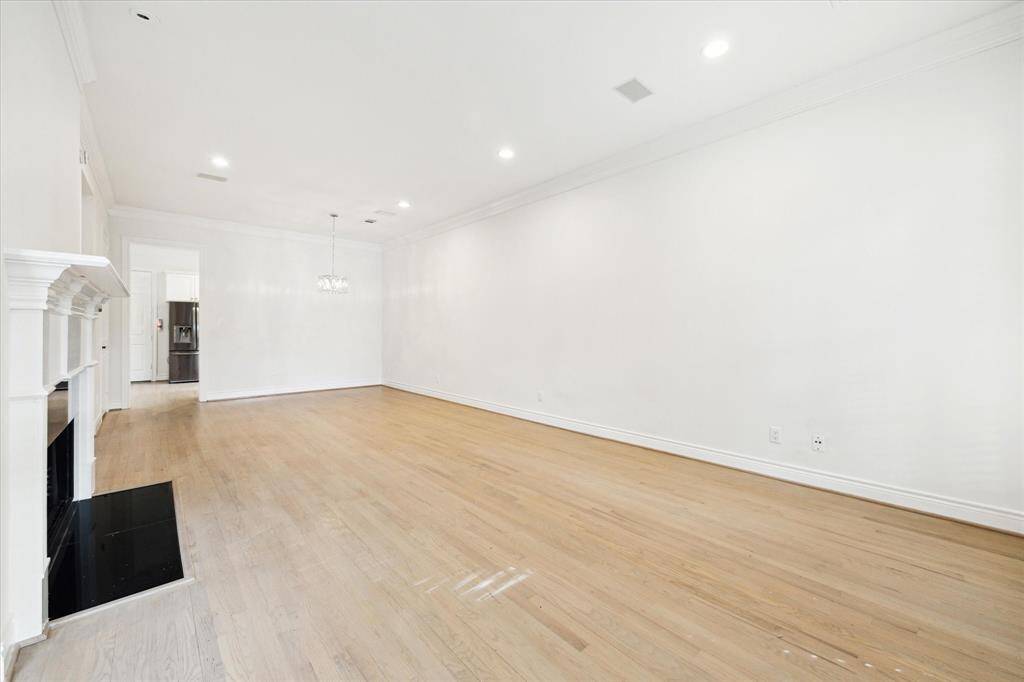 Spacious, open living / dining area with hardwood flooring, crown molding, fireplace.