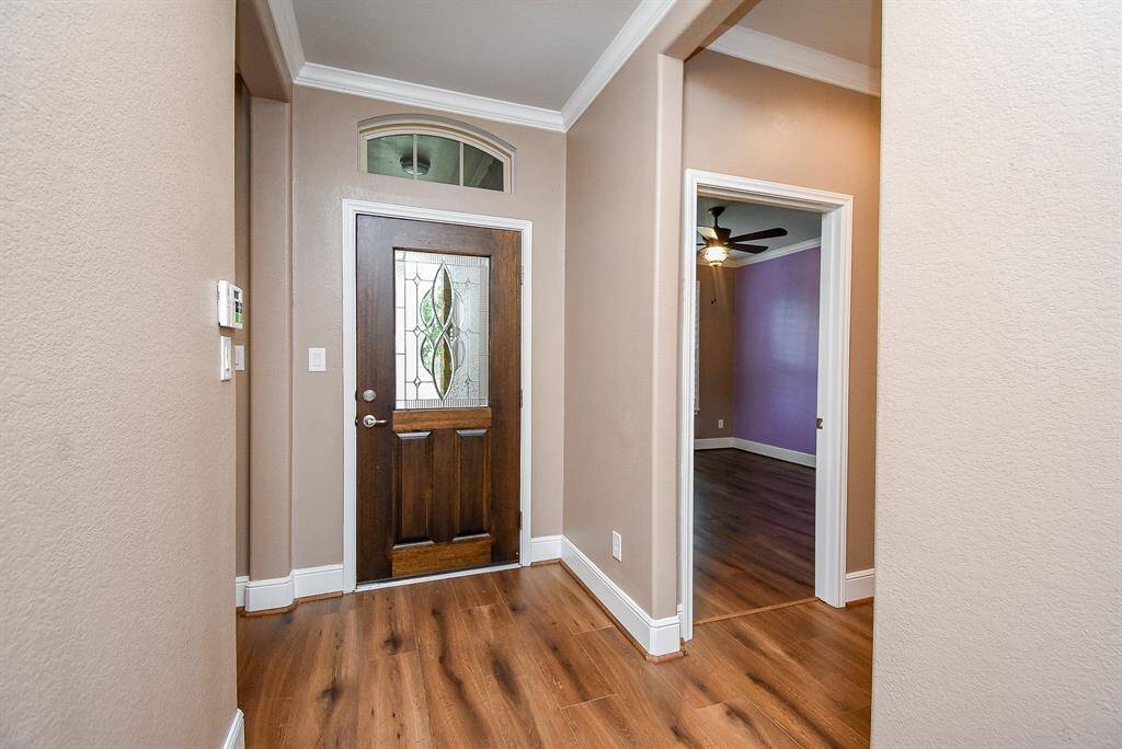 Welcoming entryway with warm-toned LVP flooring and an elegant front door featuring a decorative glass insert.