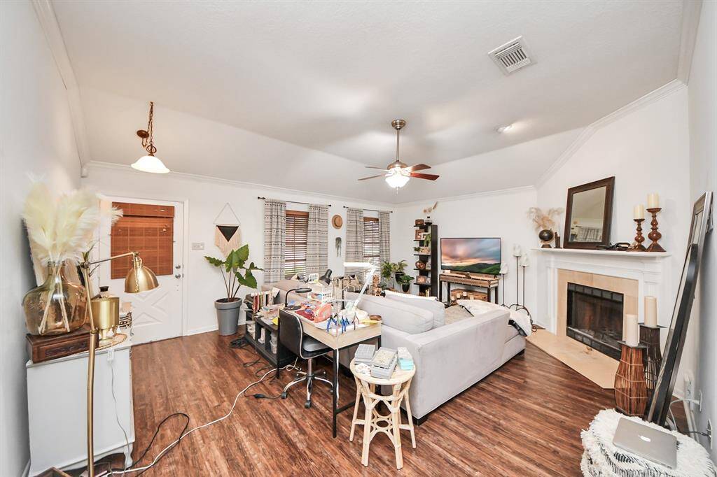 Living room features beautiful flooring, aceiling fan, high ceilings, and large windows.