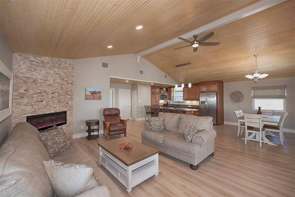 Experience seamless living in this open-concept family room, kitchen, and dining area, highlighted by a stunning floor-to-ceiling stone wall with an electric fireplace.