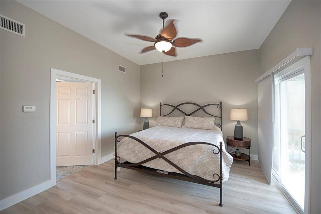 Spacious primary bedroom in soothing sage, featuring a private balcony and ample space for a king-sized bed.