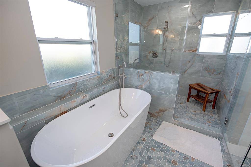 The bathroom boasts a luxurious soaking tub and a spacious walk-in shower.