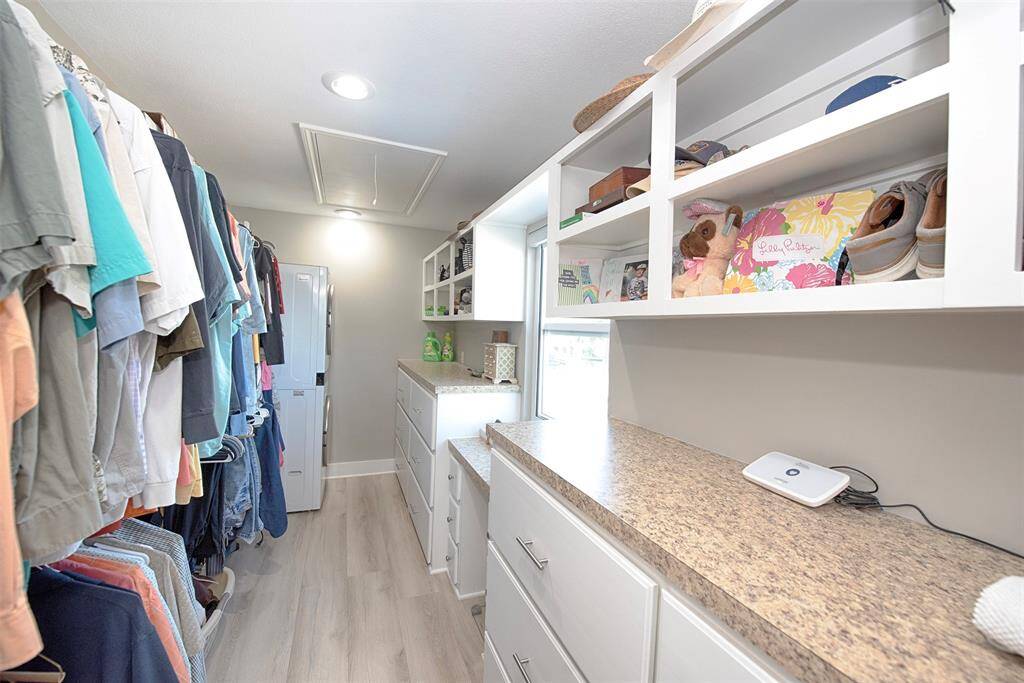 Spacious walk-in closet with room for a stackable washer and dryer, featuring elegant built-in drawers and shelving for optimal organization.