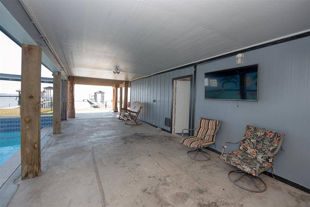 Enjoy poolside entertainment in a covered area with a TV setup. The adjacent doorway leads to a versatile workshop and flex room with a full bath.