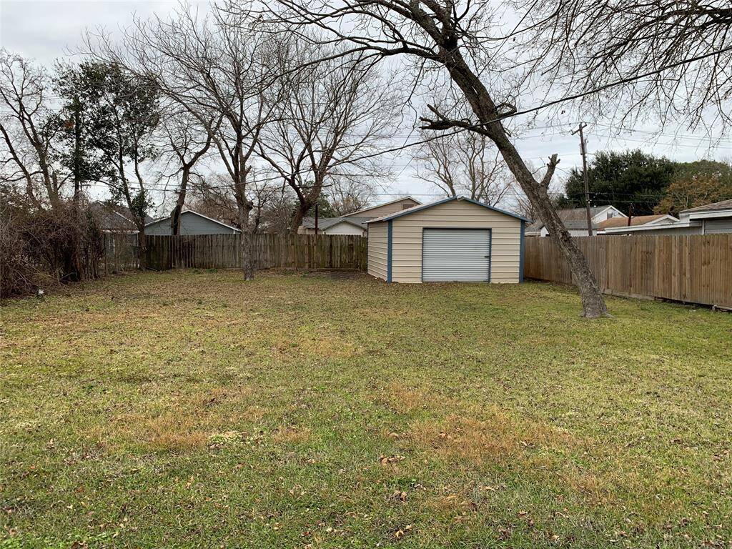 Fenced backyard with storage building and double gate.