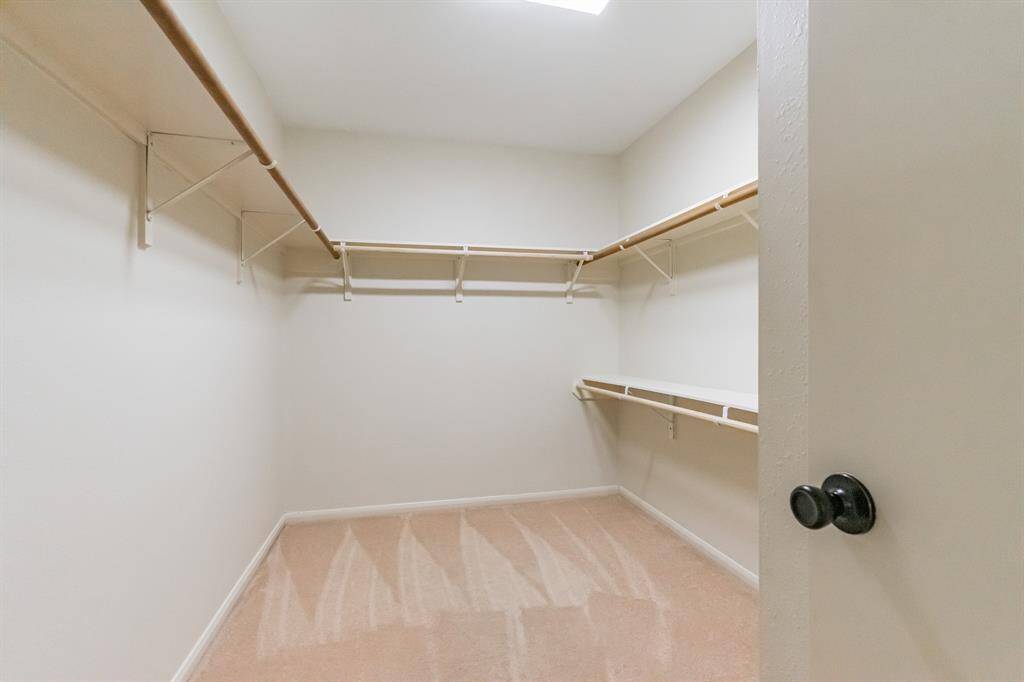 The primary bathroom showcases with a large mirror, ample counter space, and multiple light fixtures. The wooden cabinetry provides storage, and there's a seated vanity area. Neutral wall colors give a warm, inviting feel.