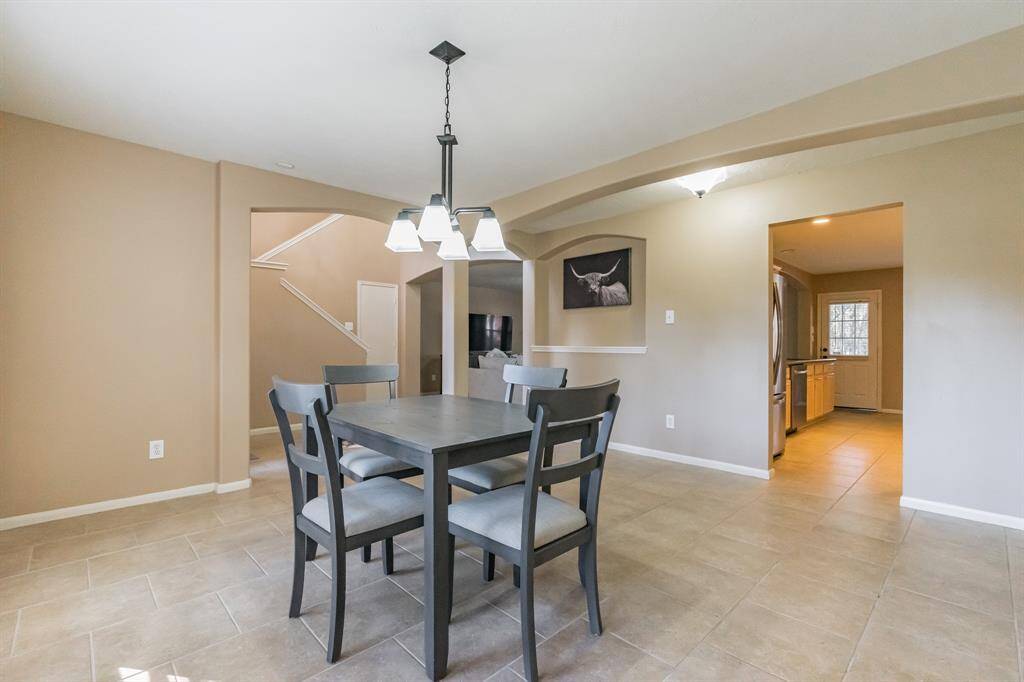 Dining (or study) area with large arched windows, neutral wall colors, and tiled flooring.