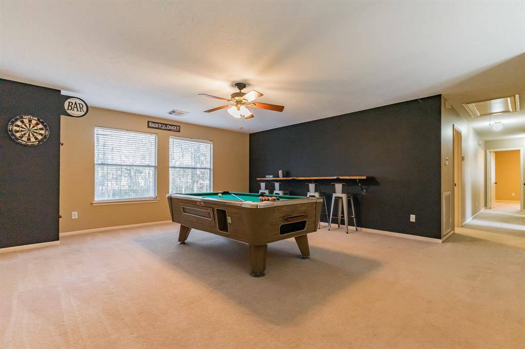 A spacious, open dining area with neutral tones, tile flooring, and modern lighting. It connects to a kitchen with stainless steel appliances and features a nearby staircase, offering a welcoming and functional layout.