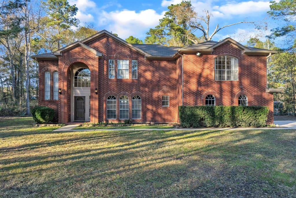 This charming two-story brick home features large windows and a stately entrance. Surrounded by mature trees, it offers a spacious front yard and a serene setting, perfect for family living.