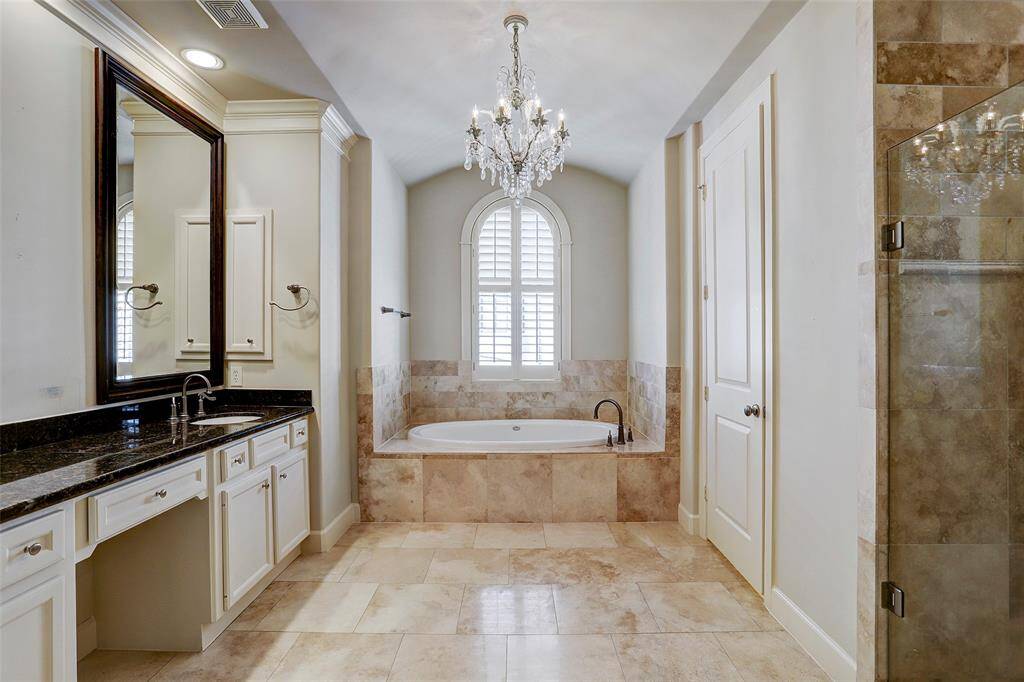 Crystal chandelier accentuates the beauty of the lavish master bath. Granite countertops, tile surround tub, seamless shower, recessed lighting and crown molding complete the room.