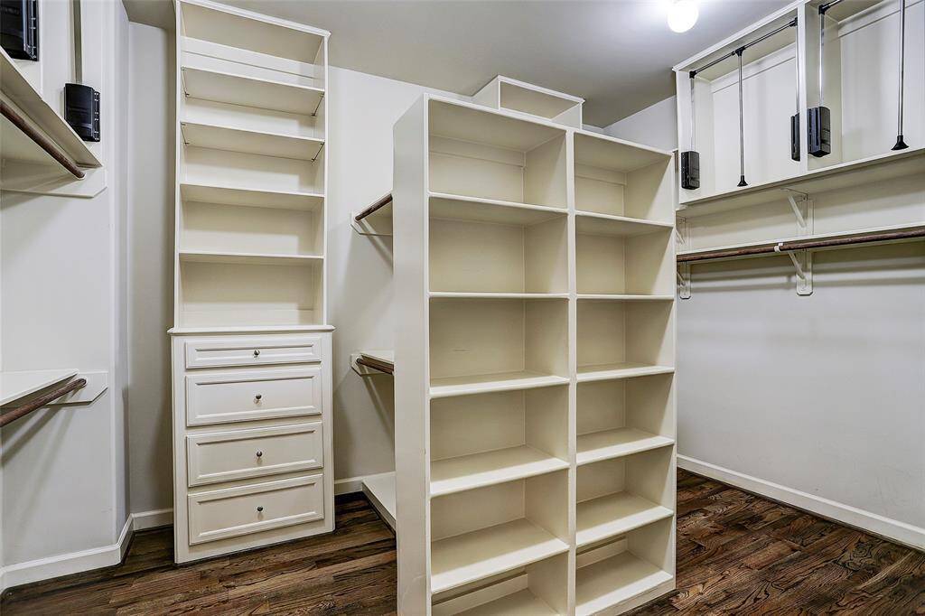 Extremely well planned custom-fitted walk-in closet with abundance of hanging rods, chest of drawers, numerous built-ins and hardwood floors.