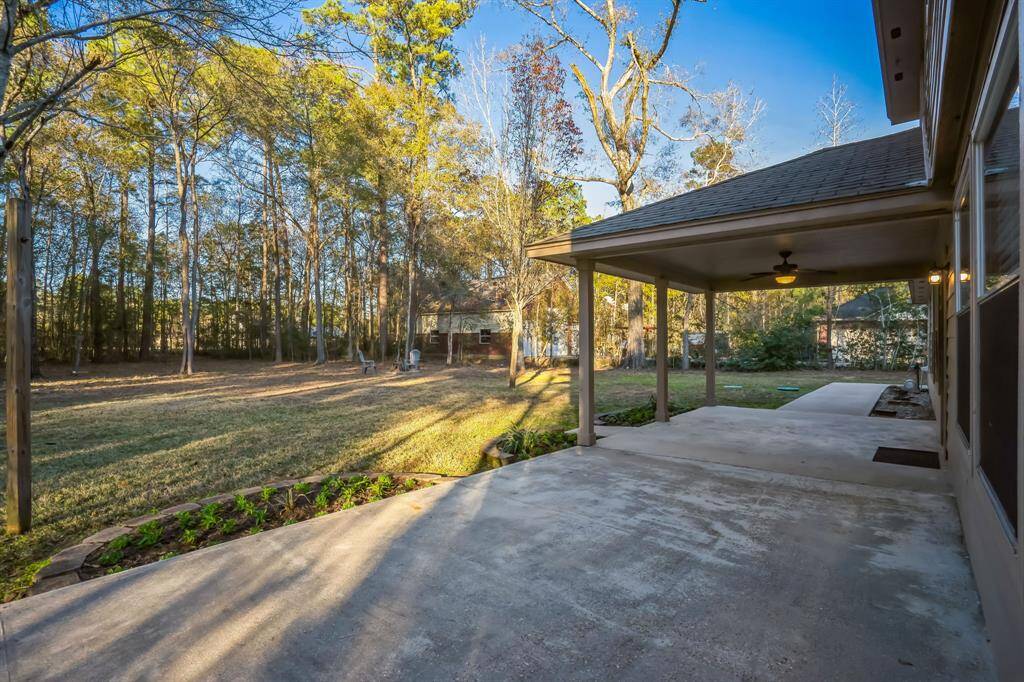 Wonderful patio areas both covered and uncovered, perfect for outdoor relaxation and entertainment. The yard is bordered by tall trees, offering privacy and a natural setting.