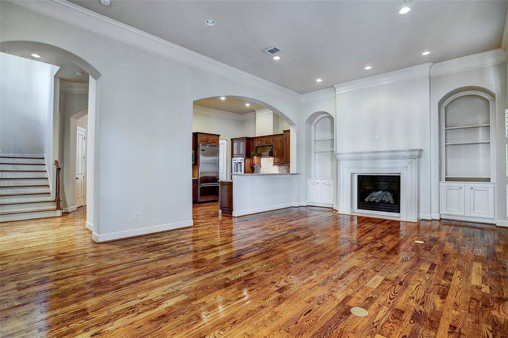 A handsome fireplace flanked by arched bookcases, serves as the centerpiece of the living room where gorgeous hardwood floors, crown molding and high ceilings give definition to the quality-laden room.
