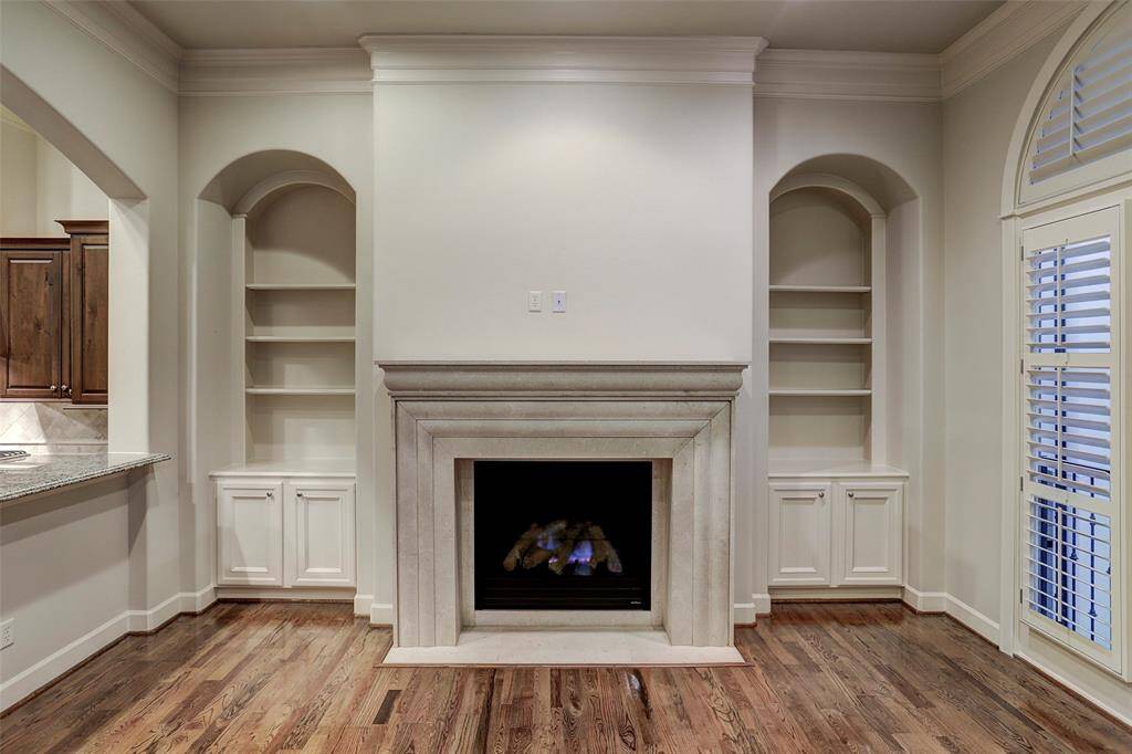The lovely living room invites you to relax and unwind in front of a gas fireplace with a stone surround. Art lighting illuminates the beautiful built-in shelving and cabinetry.