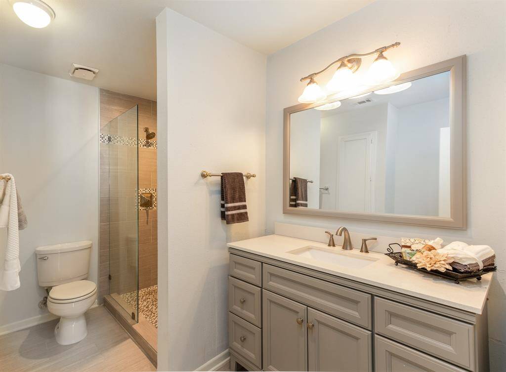 The updated primary bathroom offers a large shower, updated vanity and built in storage.