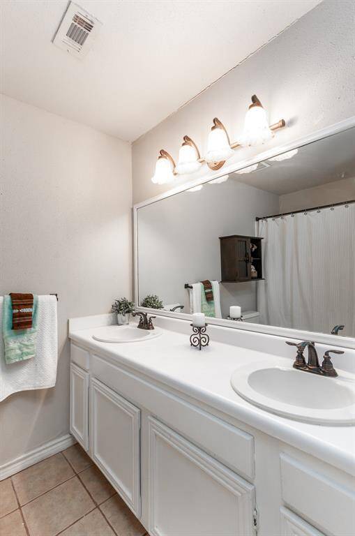 This super spacious bathroom upstairs features double sinks, tile floors and neutral colors.