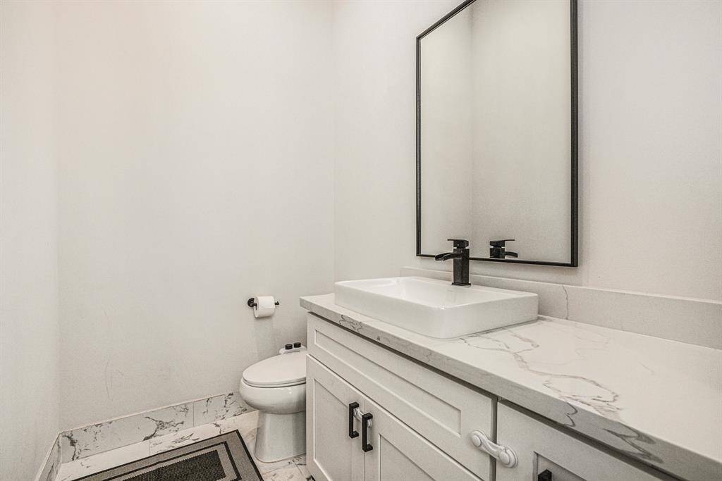 This is a modern bathroom featuring a sleek white vanity with a black faucet, a large rectangular mirror.