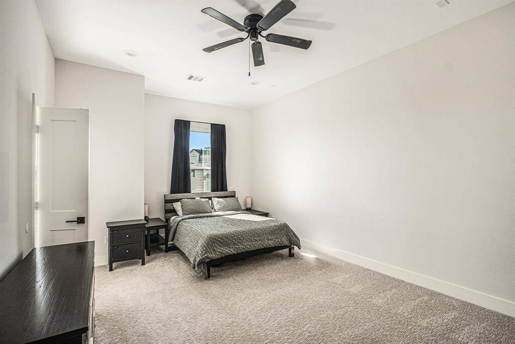 This spacious bedroom features neutral walls, plush carpeting, and a ceiling fan. It includes a window for great lighting.  Primary bathroom off to the side.  Additional closet in the bedroom.
