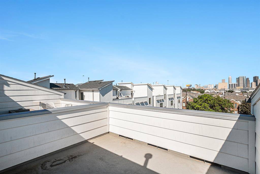 This photo showcases a rooftop patio with a clear view of the city skyline in the distance. Ideal for enjoying outdoor space in an urban setting.