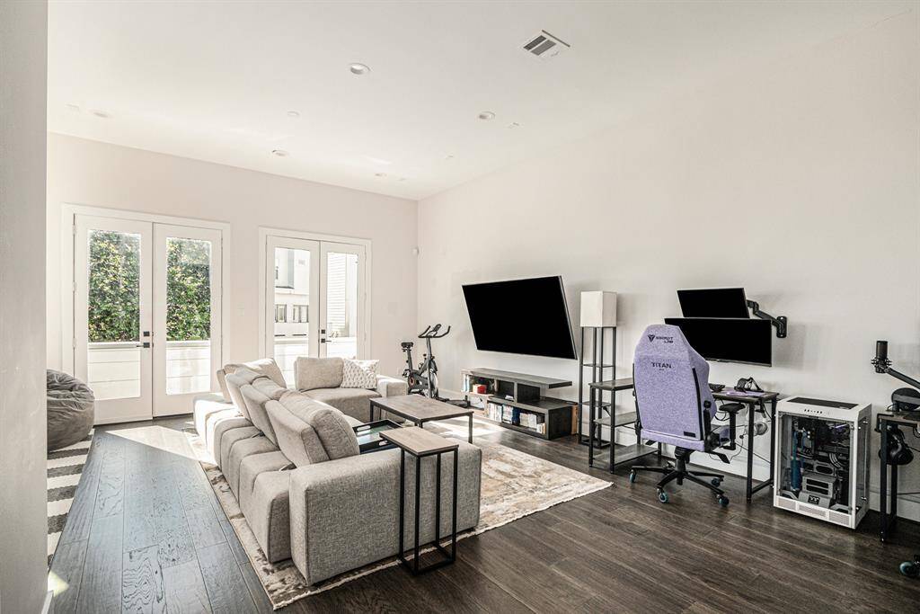 This room features a modern, open design with natural light streaming through French doors. It includes a comfortable seating area.