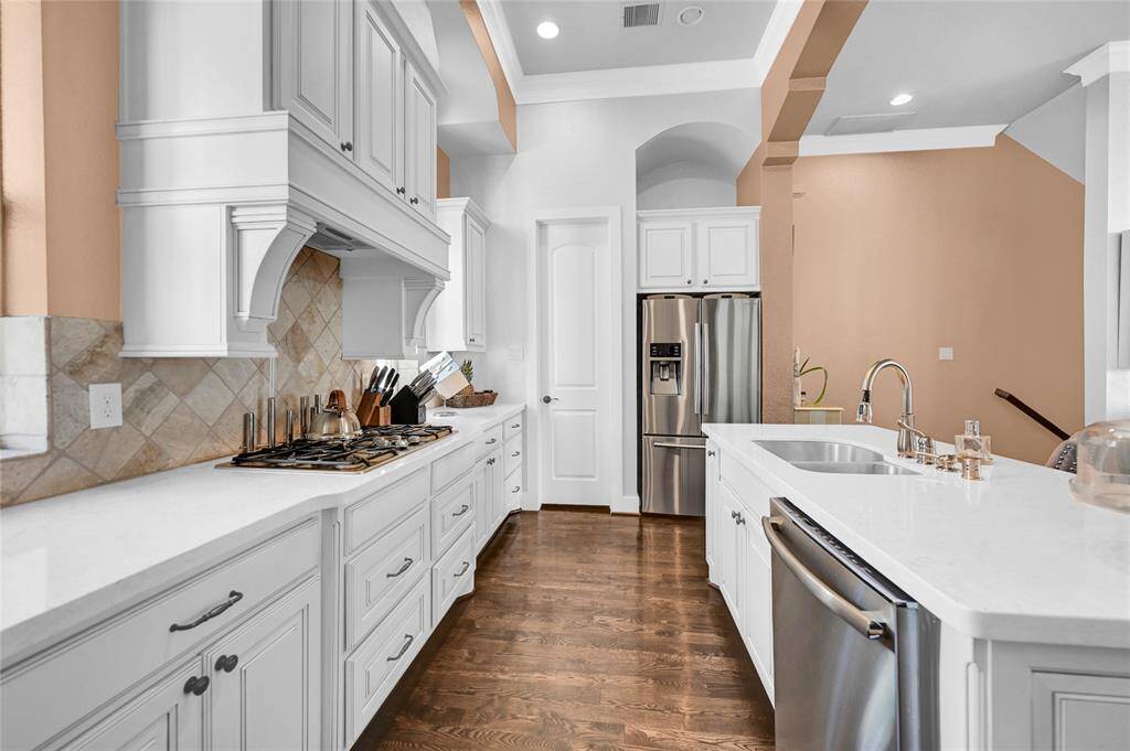 Custom white kitchen is a dream boasting hardwood flooring, Qurartz countertops and custom cabinetry