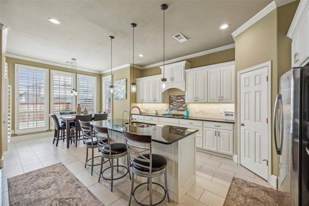 Gourmet Kitchen with white tall cabinetry, stainless steel appliances, sink, and an island with sink. Lantana Golf Course