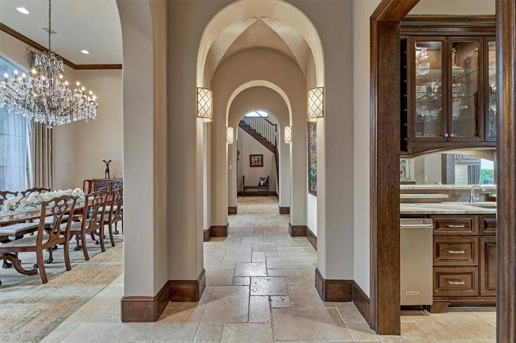 A unique arched hallway with a custom pearl finished groin vault ceiling connects the dining room to the kitchen and bar area. This hallway also leads to the half bath for guests.