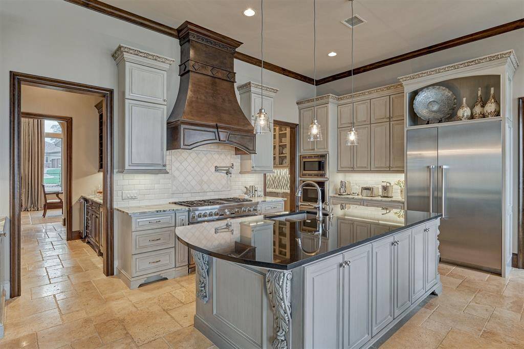The chef's kitchen features an elegant vent hood, pot filler, Thermador appliances, and custom-built cabinets with port and spice drawers. Specialty appliances like a steam oven and warming drawer enhance the culinary experience. With 6 burners and 3 ovens to use, you'll never run out of cooking space!