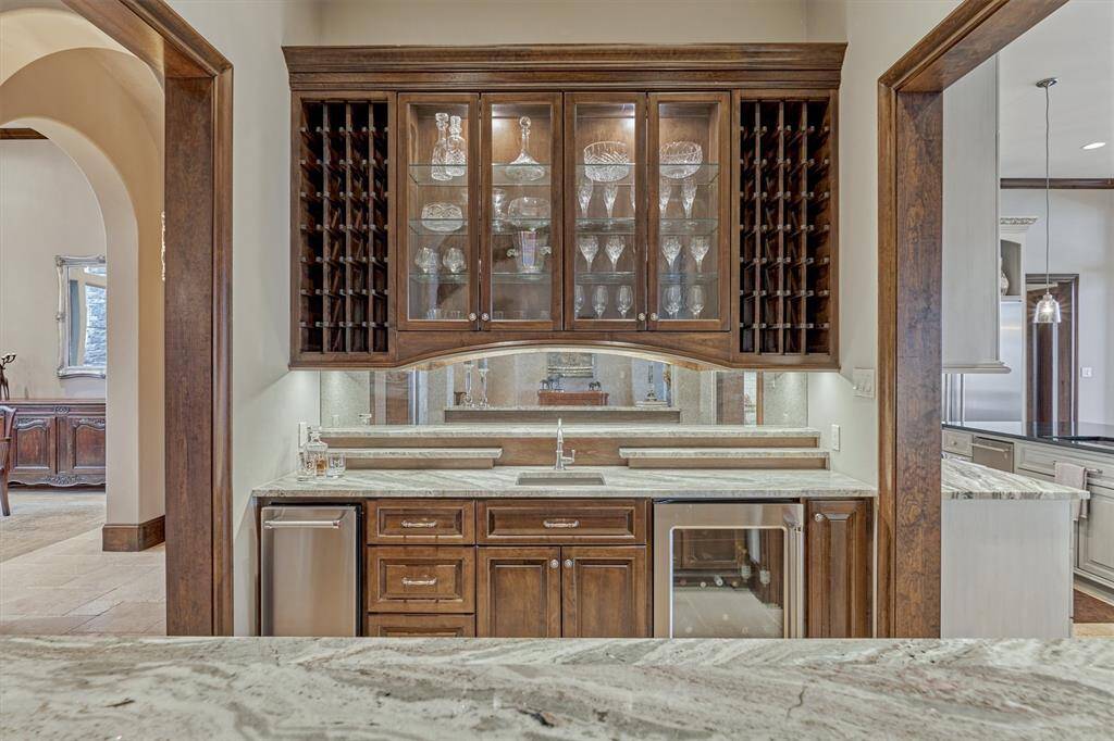 Thoughtfully located in the center of the entertaining areas, the custom bar area provides the perfect spot to entertain guests with a wine rack for 64 bottles, beverage fridge and sink. The glass cabinet doors and unique tiered granite backsplash offer display areas for glasses and spirits.