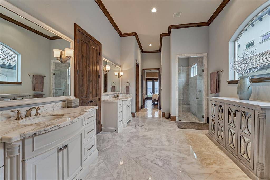 The oversized shower has a rain shower head and seamless glass enclosure. The built-in cabinet below the window can be removed to add a future tub, if desired. Plumbing is already in place and hidden inside the cabinet.
