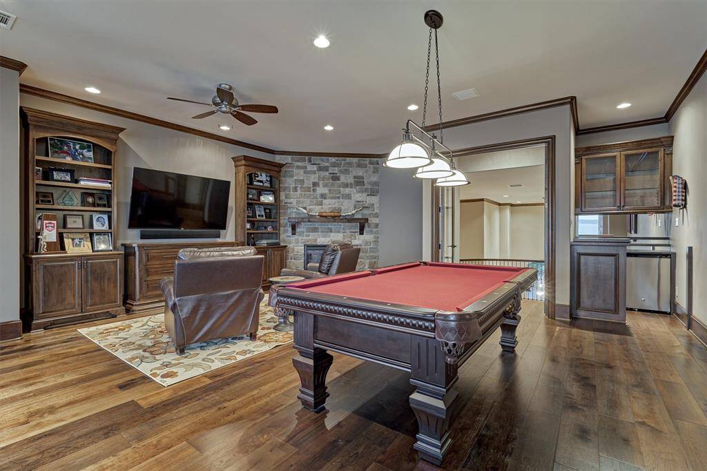 The game room is equipped with a built-in bar with mini fridge and storage for easy entertaining. A corner gas fireplace and custom built-ins finish out the room.