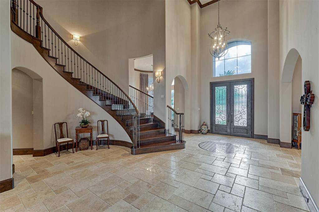 A dramatic two-story wood and iron staircase highlight the home's grand entrance.