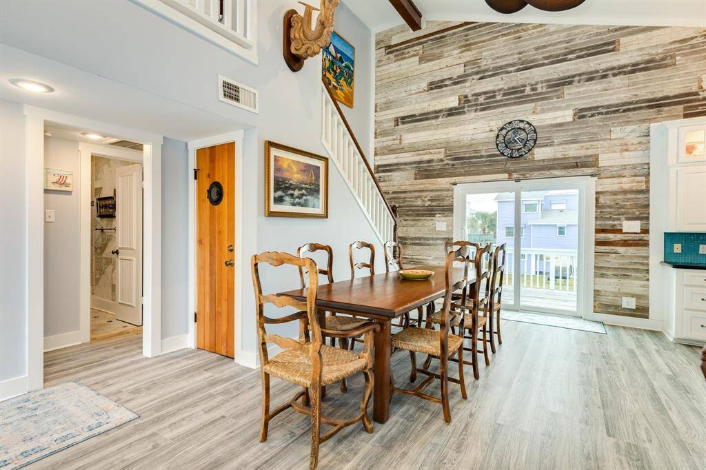 A second view of the dining area looking out towards the east deck. Large under staircase closet storage behind wooden door, and open doorway in view leads to the hall bathroom.