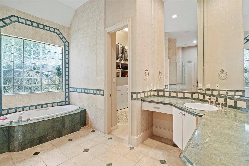 Every day is SPA day in this spacious owner's bathroom featuring a jetted soaking tub, large glass walk-in shower, two vanity areas, two large walk-in closets with built-ins, two private water closets, and a linen closet.