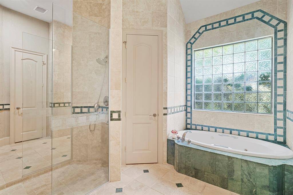 The owner's bath is essentially TWO bathrooms in one with a large, central, glass walk-in shower that can be accessed from either side of the bathroom.