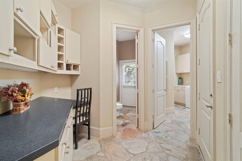 Office nook with built-in's is located next to the kitchen. Other adjoining rooms pictured include the laundry room and a half bathroom with a door to the pool area.