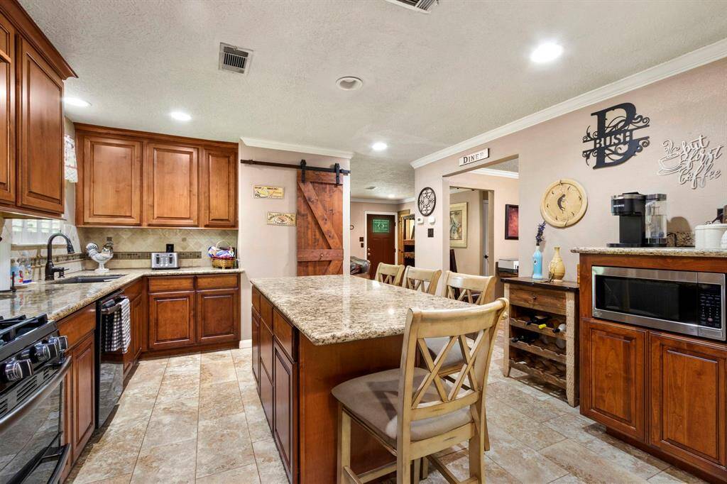 Awesome remodeled kitchen, large island with granite counter top and seating for four. Custom cabinetry, coffee station, double oven with gas cook top. Barn door covers the in kitchen pantry. The butler's pantry is across from the utility room.