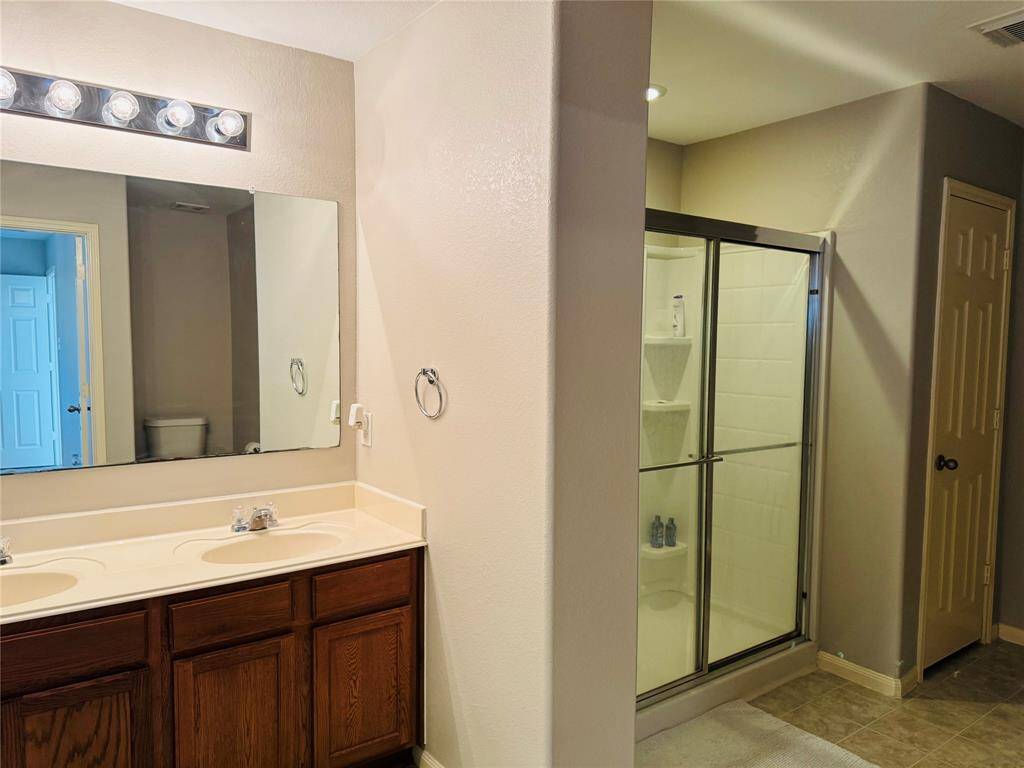 Upstairs primary bath with dual sinks, shower,  and walk in closet