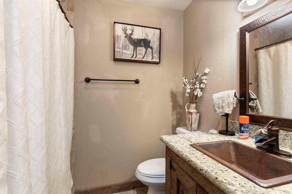 Secondary bathroom has granite counter tops and a hammered copper sink.